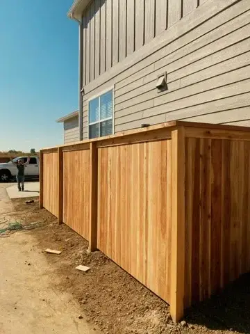 Cedar fence installation next to a new home
